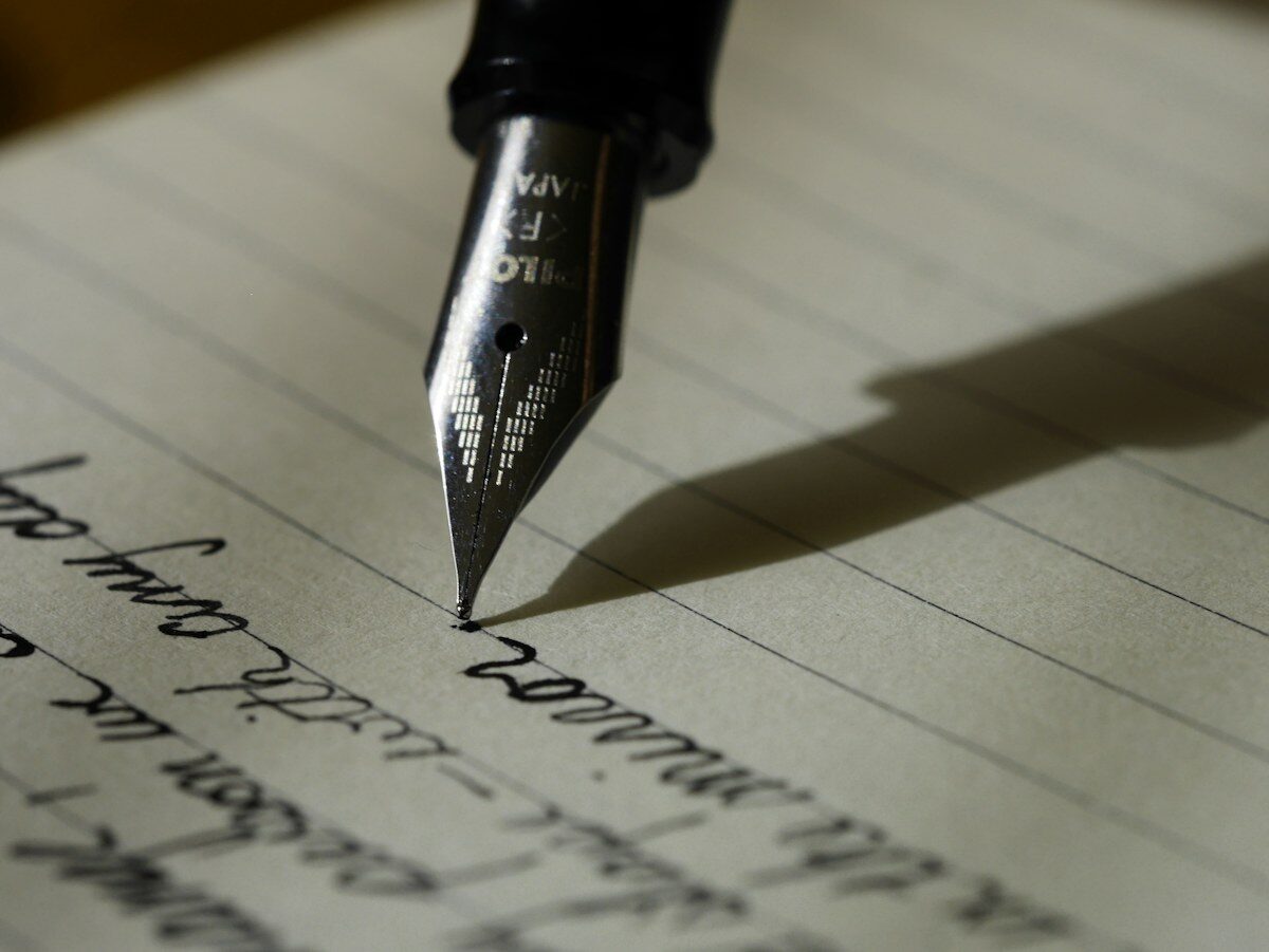 A fountain pen writing in a lined notebook