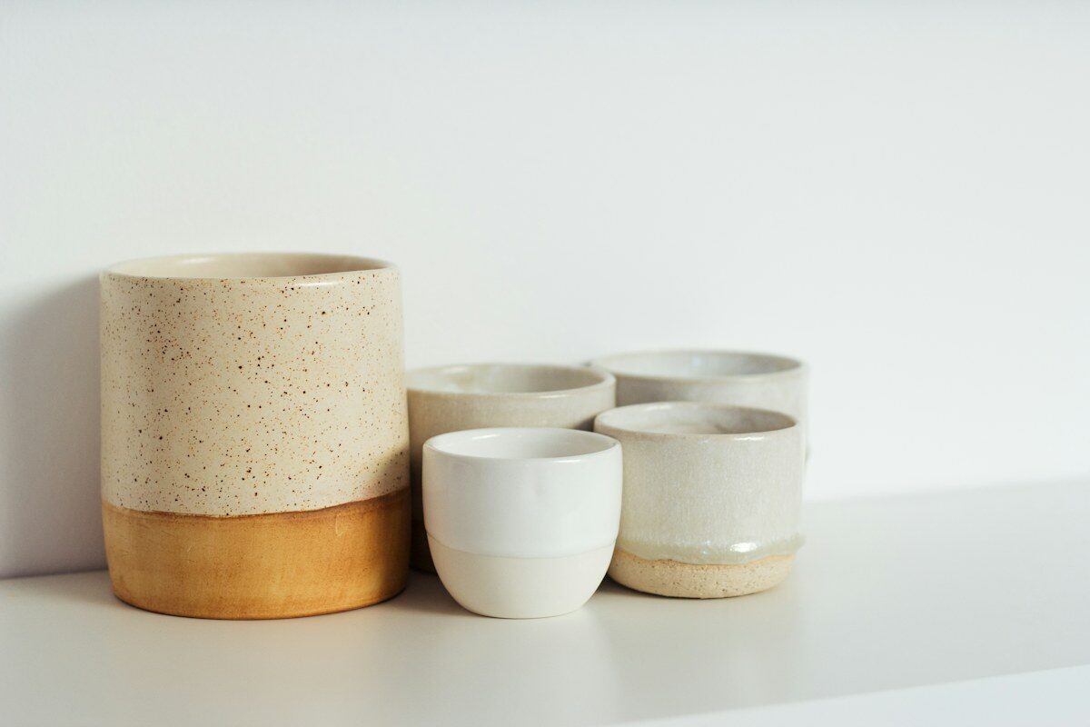 A group of handmade ceramic cups in cream and ochre